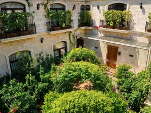 Un edificio de varios pisos con balcones, plantas en macetas y un patio interior.