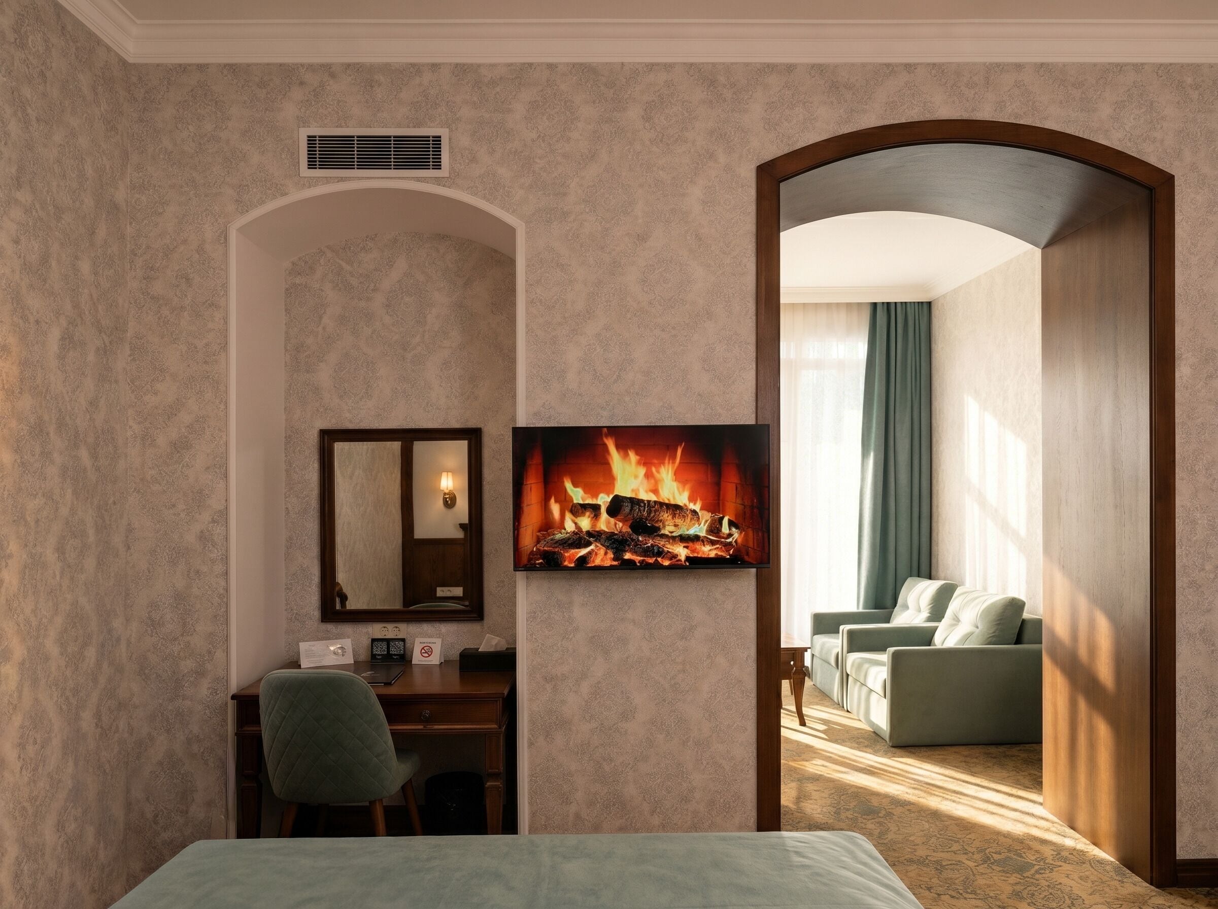 A hotel room with a bed, desk, chair, and a fireplace.