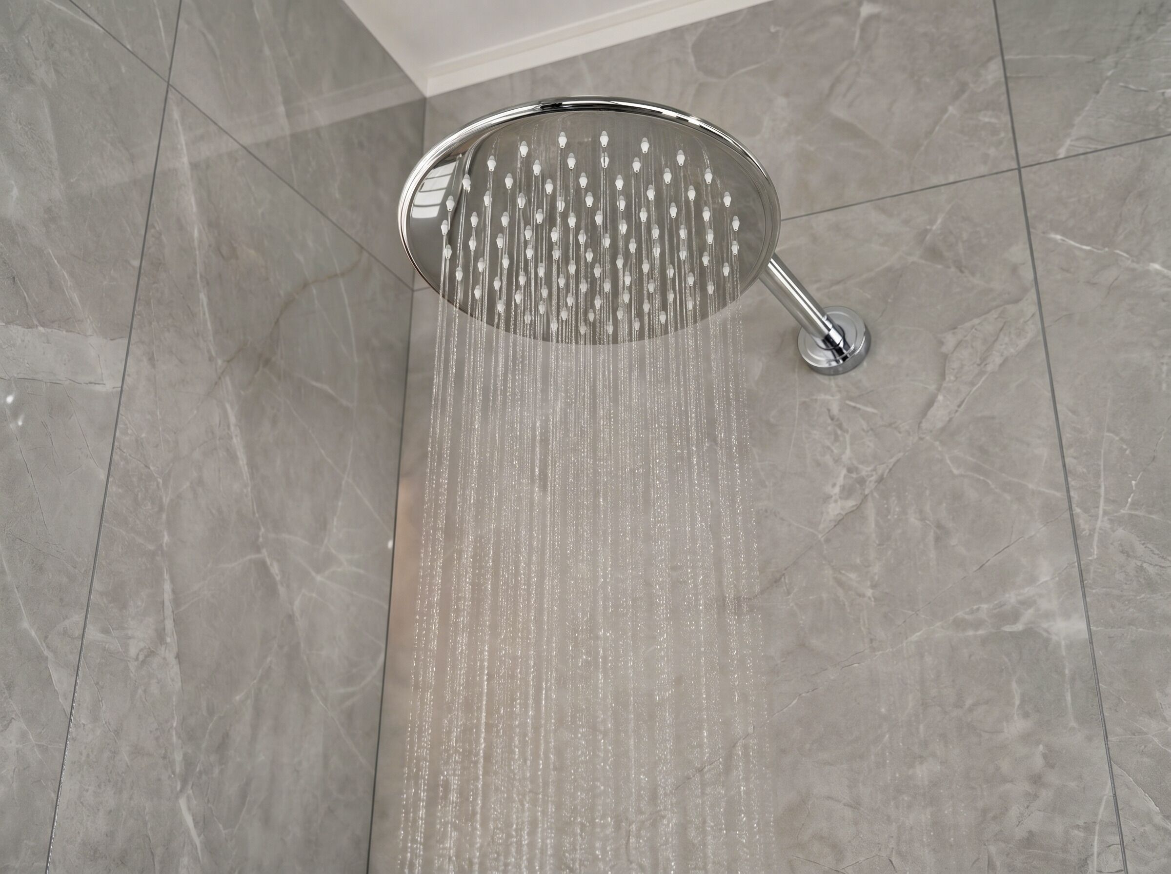 A showerhead with water flowing down a tiled floor.