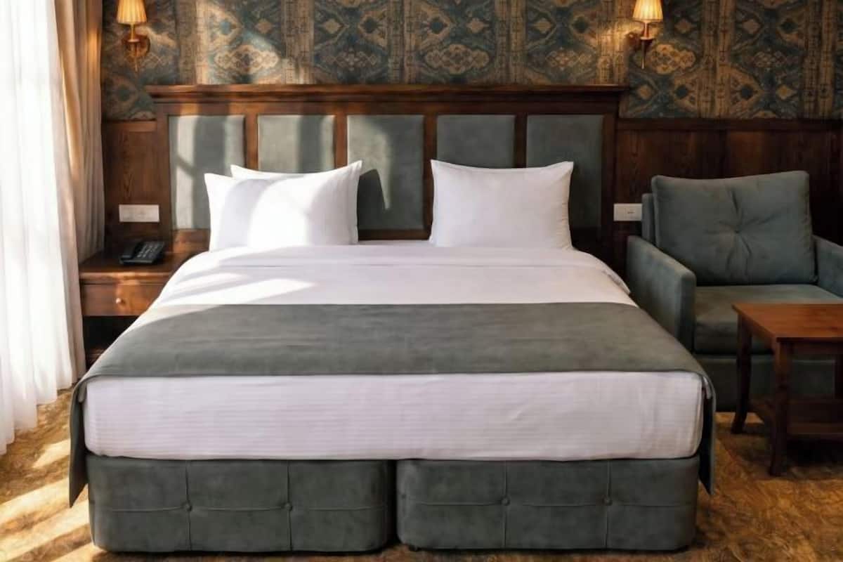 A large bed with a headboard, two bedside tables, a chair, and a small table.