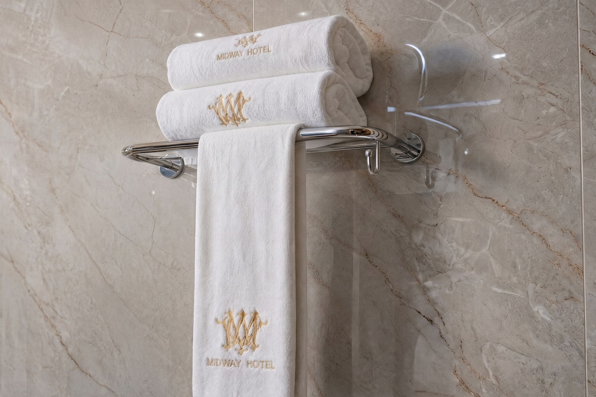 A towel rack with two towels, one rolled and one folded, both with embroidered text.