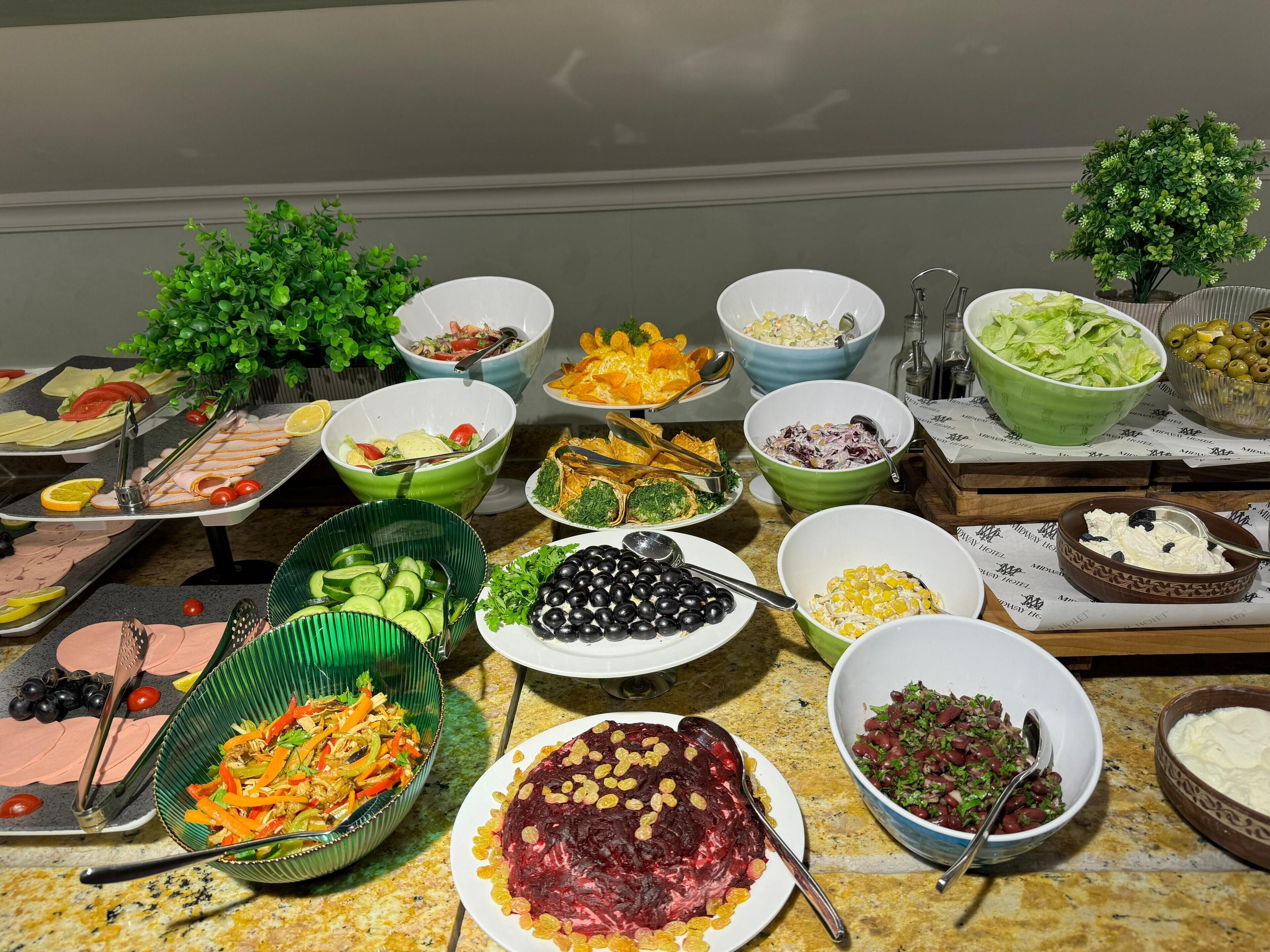 Une table de buffet proposant divers plats, notamment des salades, des fruits et des viandes.