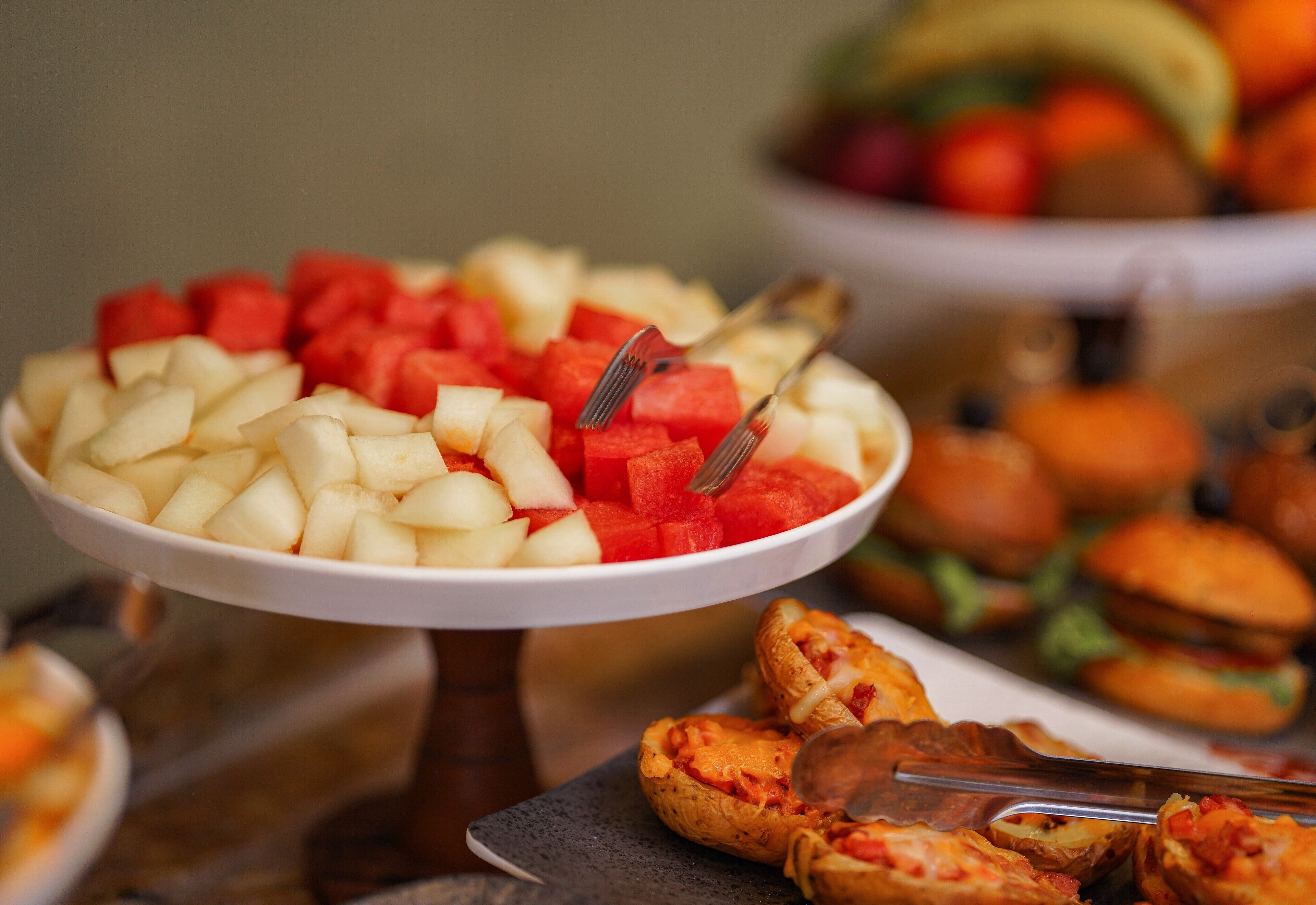 A buffet with various food items including diced apples, watermelon, and sandwiches.