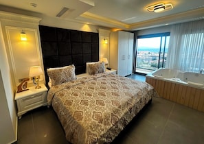 Une chambre spacieuse avec un grand lit, une salle de bain séparée avec un jacuzzi et une vue sur la ville.