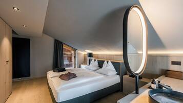 Una habitación de hotel moderna con una cama grande, mesita de noche y baño con lavamanos y espejo.