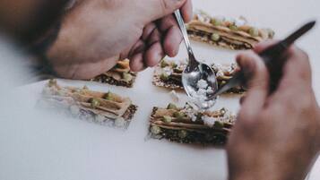 A person preparing food with a spoon and a knife on a white surface.