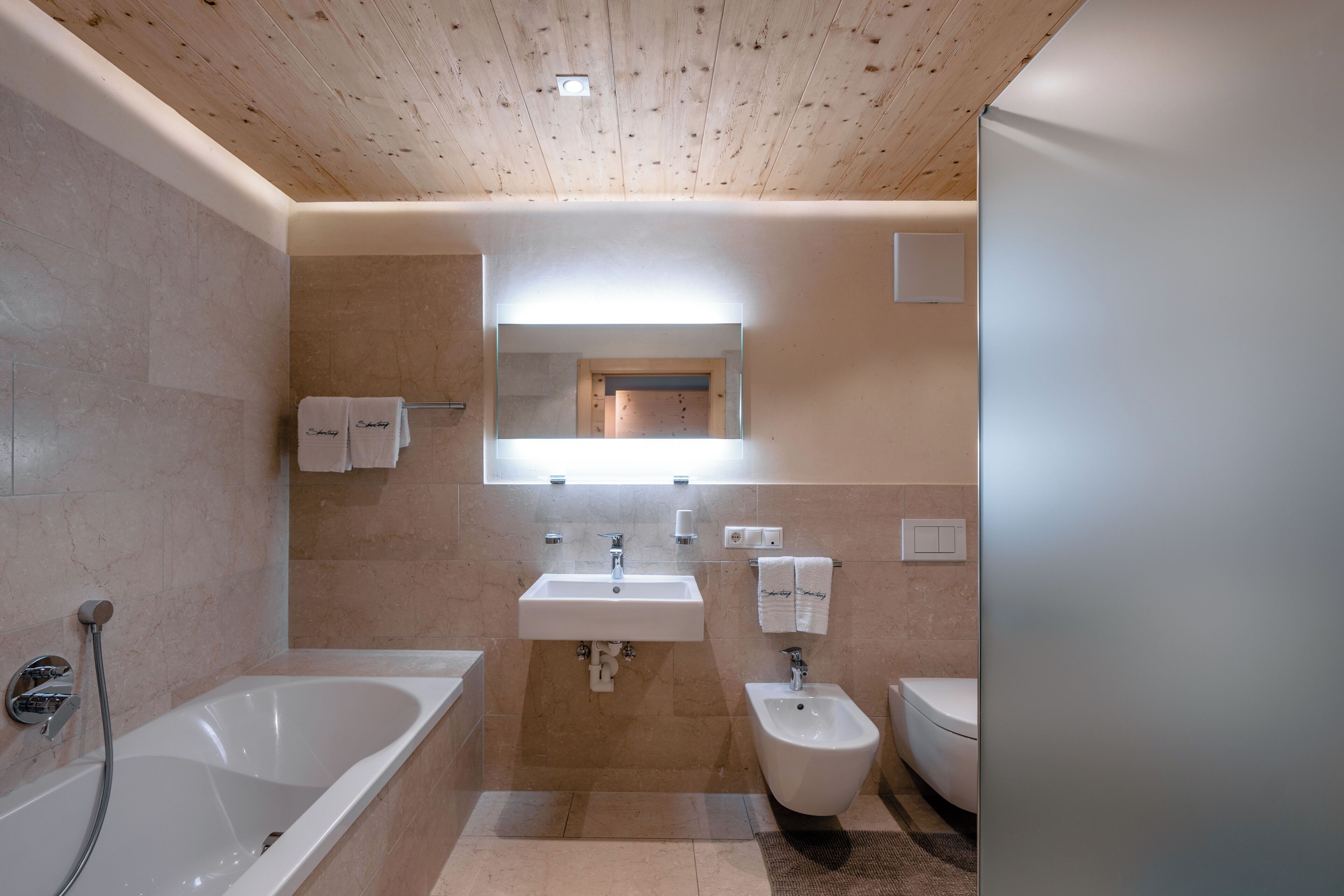 A modern bathroom with a bathtub, a bidet, a toilet, and a sink.
