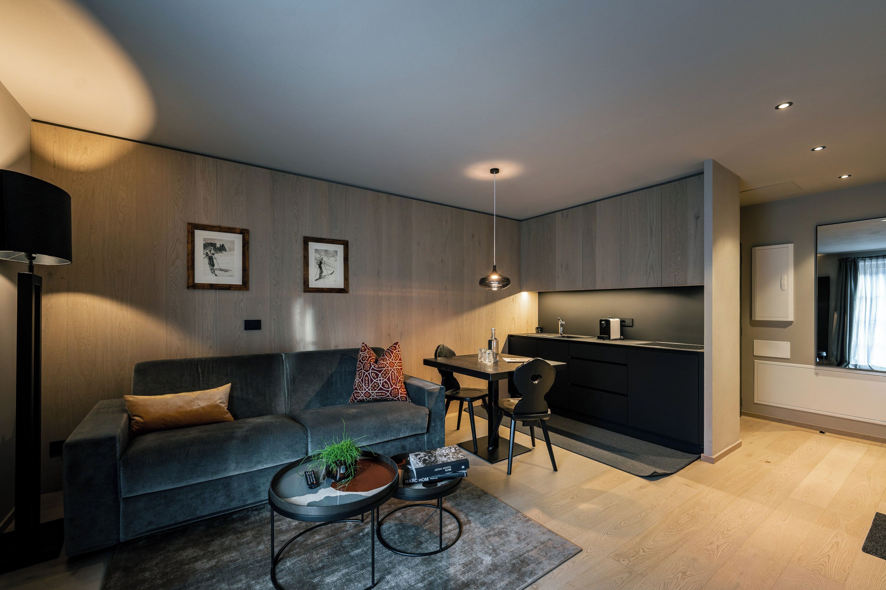 A modern living room with a grey sofa, a coffee table, and a dining area with a table and chairs.