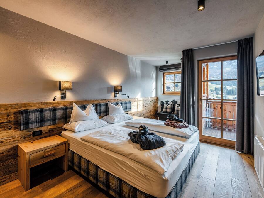 Un dormitorio con una cama grande, cabecera de madera, dos mesitas de noche y una ventana con vistas al exterior.