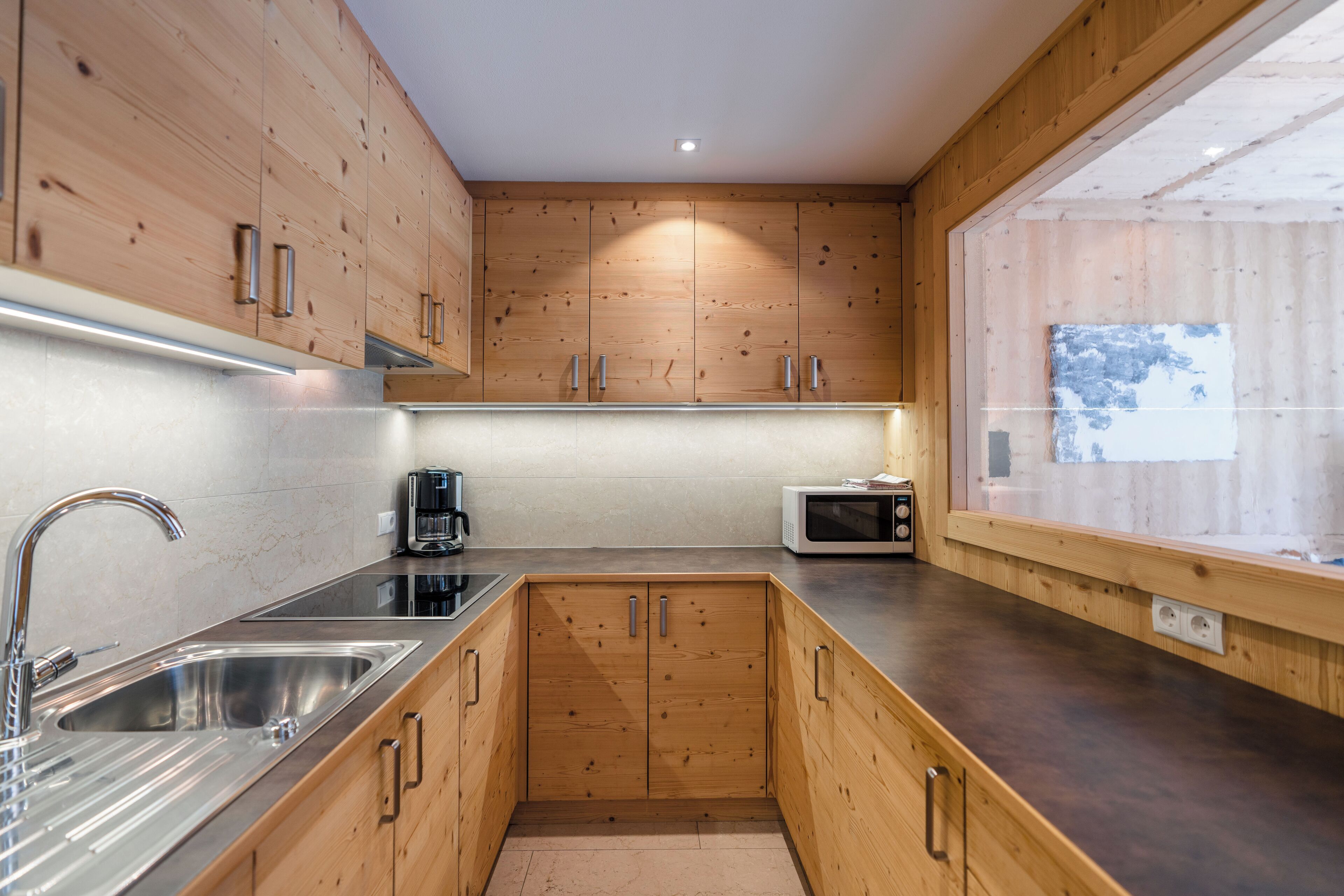 A modern kitchen with wooden cabinets, stainless steel sink, and a microwave.