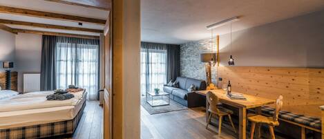 A room with a bed, a sofa, a dining table, and a bench.