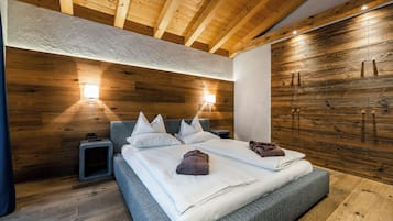 A modern bedroom with a wooden ceiling, a large bed with pillows, a bedside table, and a wardrobe.