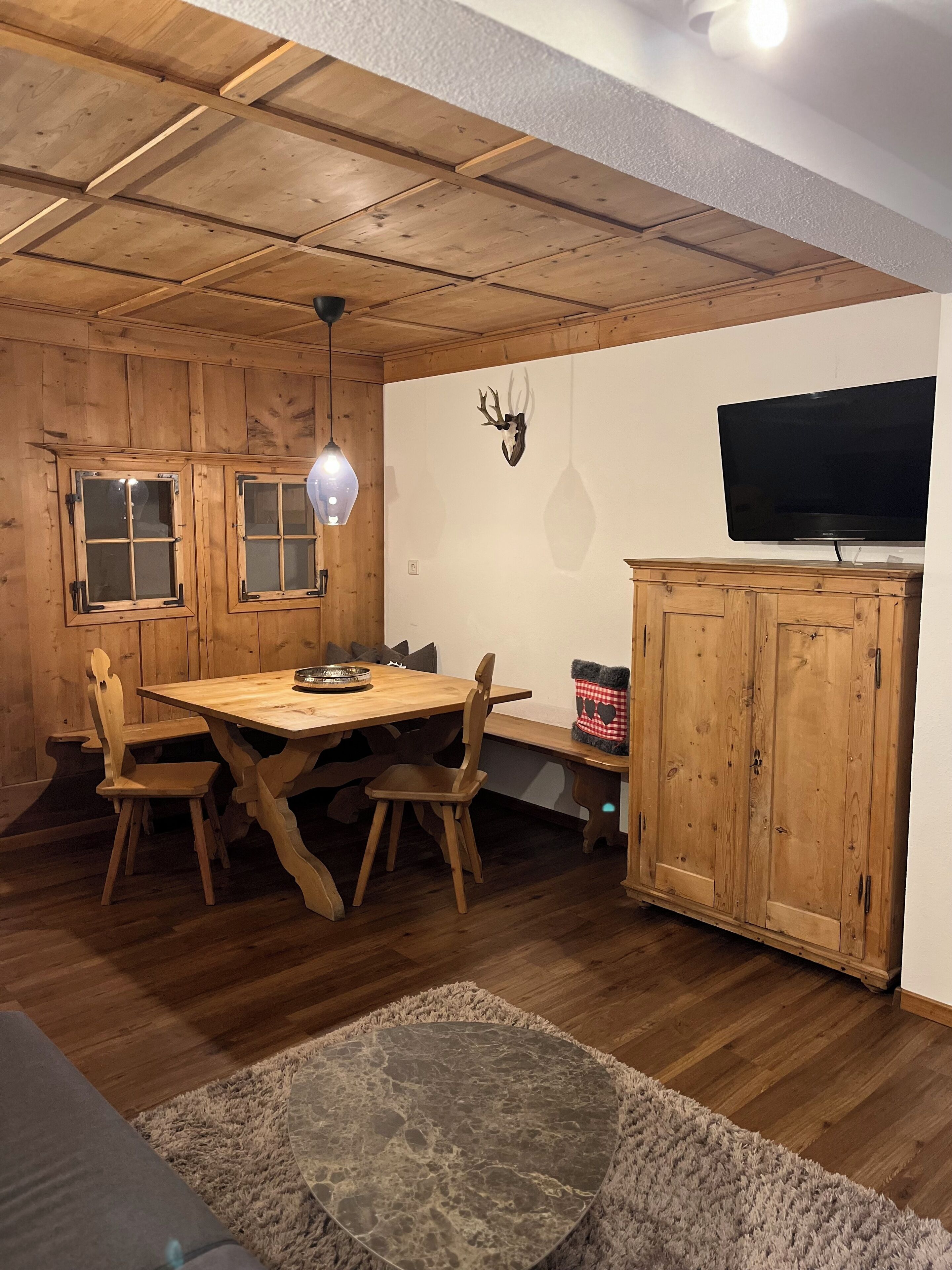 A wooden dining room with a table, chairs, and a television on a cabinet.