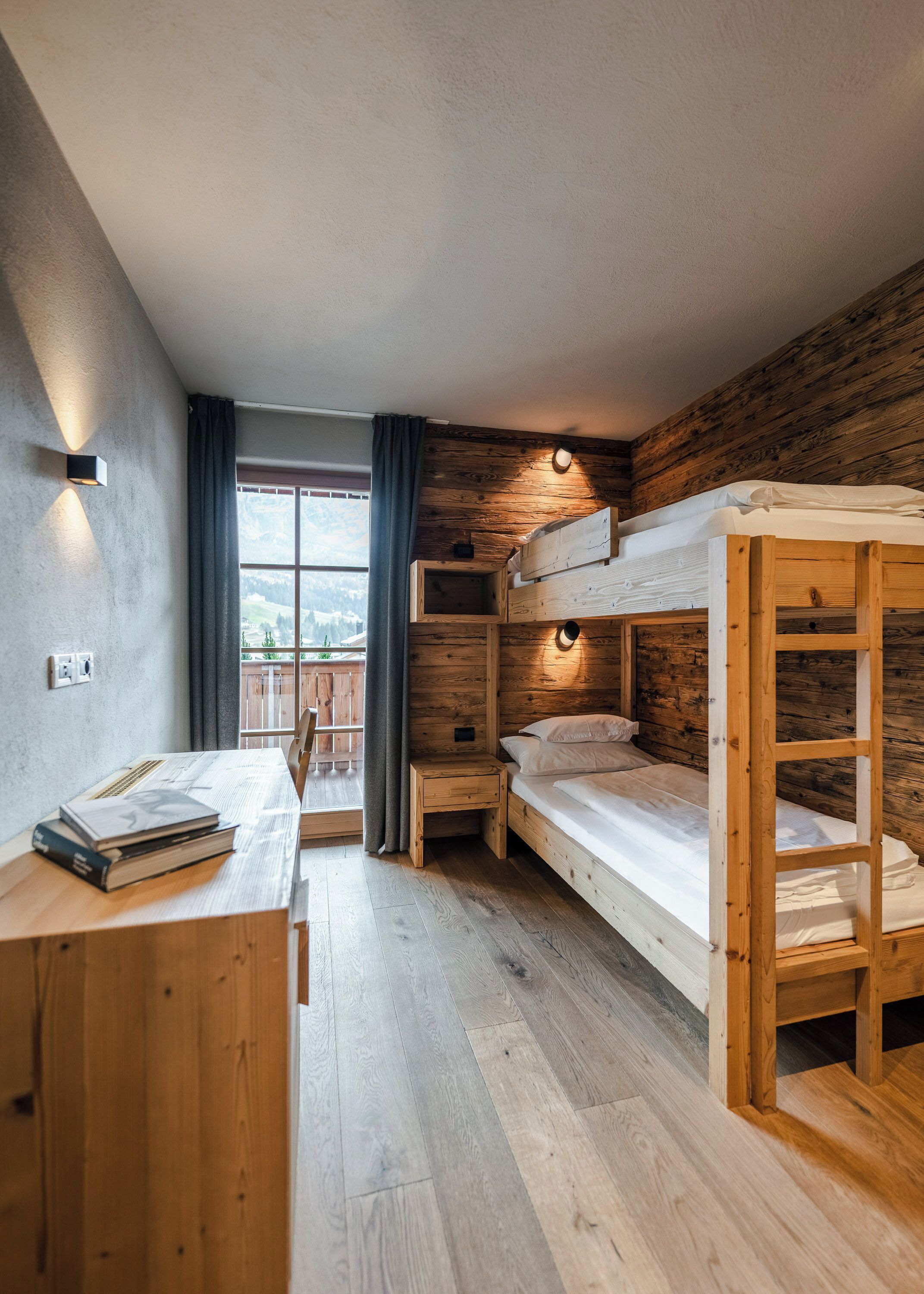 A compact room with bunk beds, a desk, and a window with curtains.