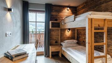 Habitación pequeña con literas, un escritorio y una ventana con cortinas.