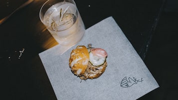 Ein Sandwich mit Tomatenscheibe und ein Getränk im Glas auf einem Servietttuch.
