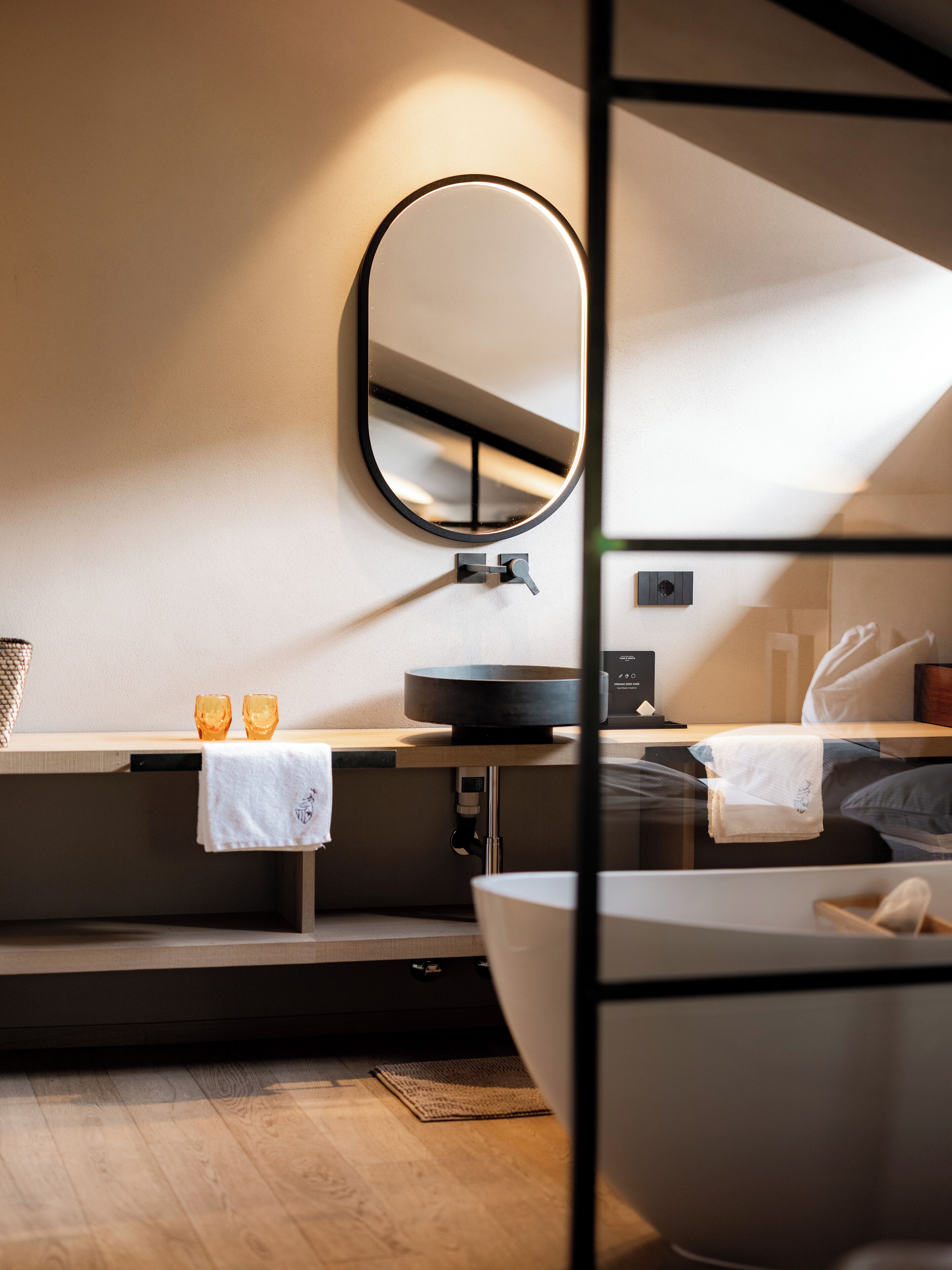 Ein modernes Badezimmer mit rundem Spiegel, Waschbecken und Badewanne.