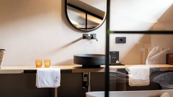 Ein modernes Badezimmer mit rundem Spiegel, Waschbecken und Badewanne.