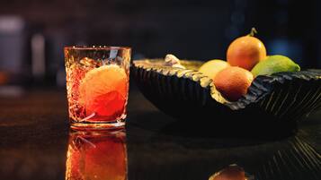 A glass with a clear liquid and a slice of orange, placed on a reflective surface.
