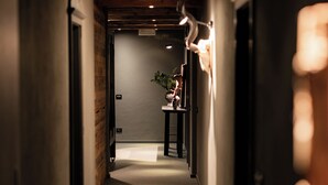 A narrow hallway with a wooden ceiling, a plant on a table, and a door at the end. - Sportony Mountain Lodges (Badia)