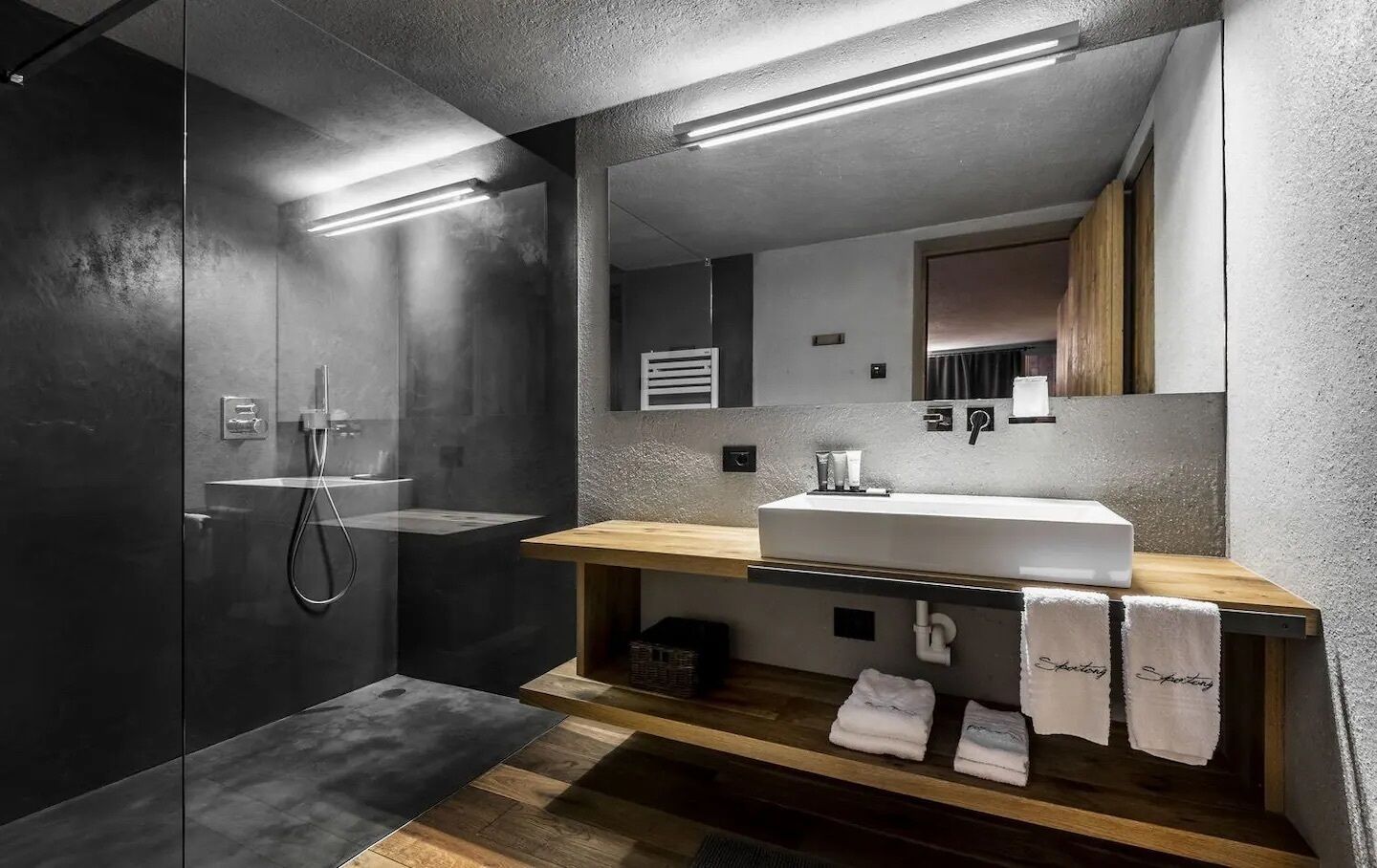 A modern bathroom with a glass-enclosed shower, a wooden vanity with a white sink, and a mirror above the sink.