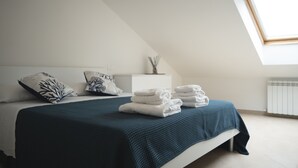 Une chambre à coucher avec un lit, des oreillers, une table de chevet et une fenêtre.