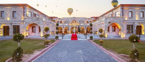 Un edificio histórico de piedra con un patio central, arcos de entrada y una alfombra roja que conduce a una entrada imponente.