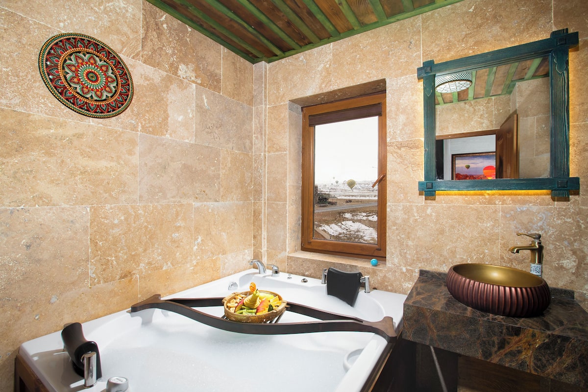 Une salle de bain avec une baignoire, un lavabo doté d’un receveur décoratif et un miroir avec un cadre en bois.