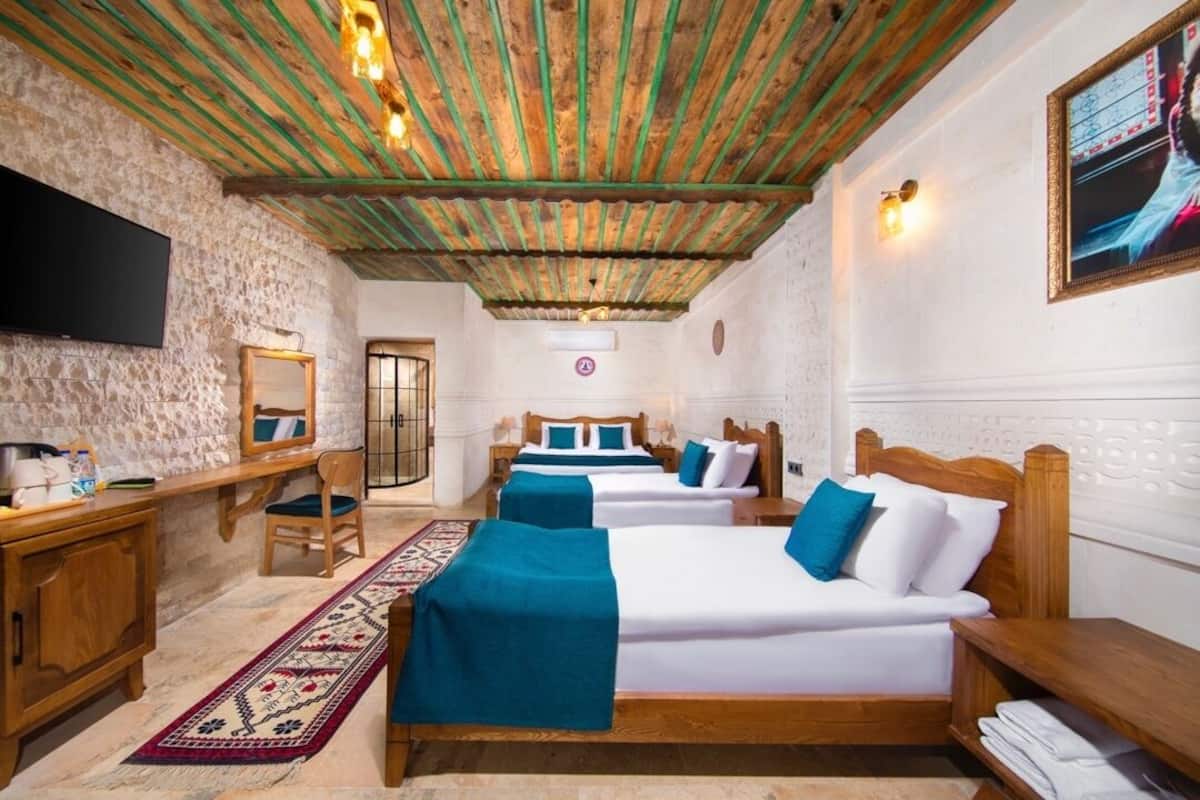 Une chambre d’hôtel avec deux lits, un bureau, une chaise, une télévision et un plafond en bois.