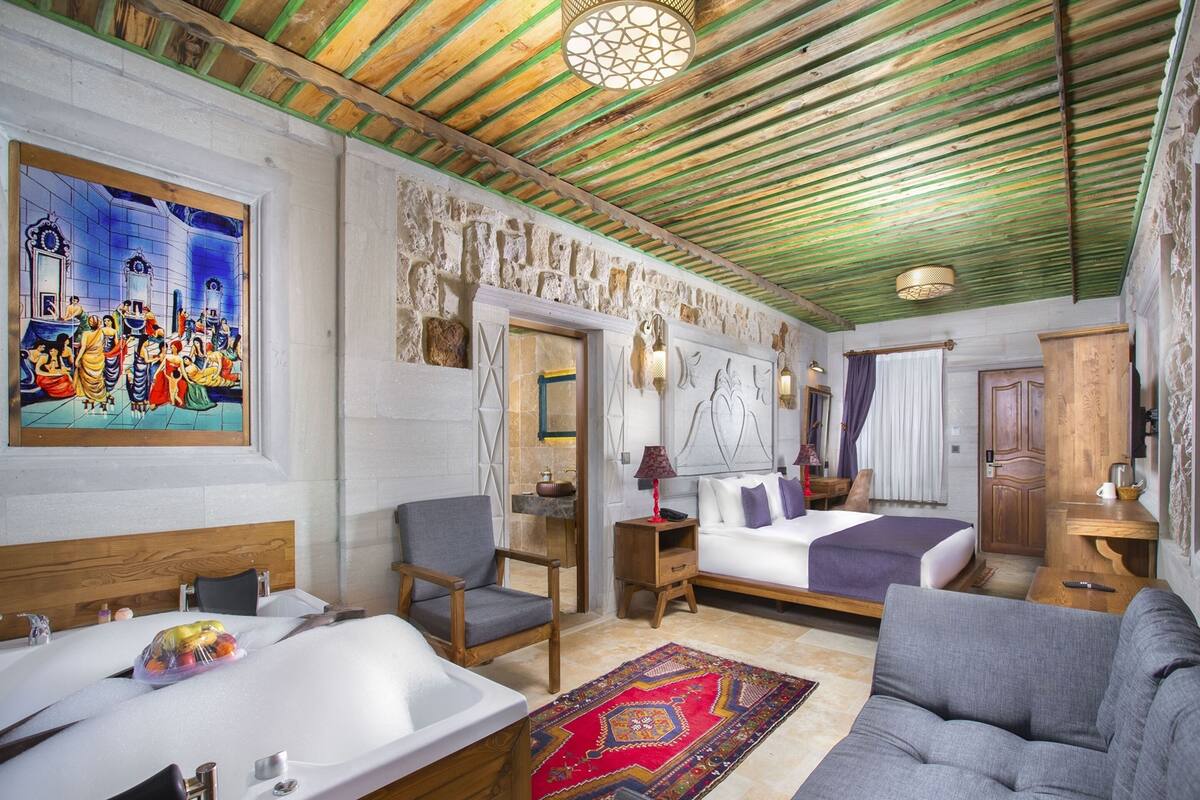 Une chambre avec un grand lit, un canapé, une baignoire et un tableau au mur.