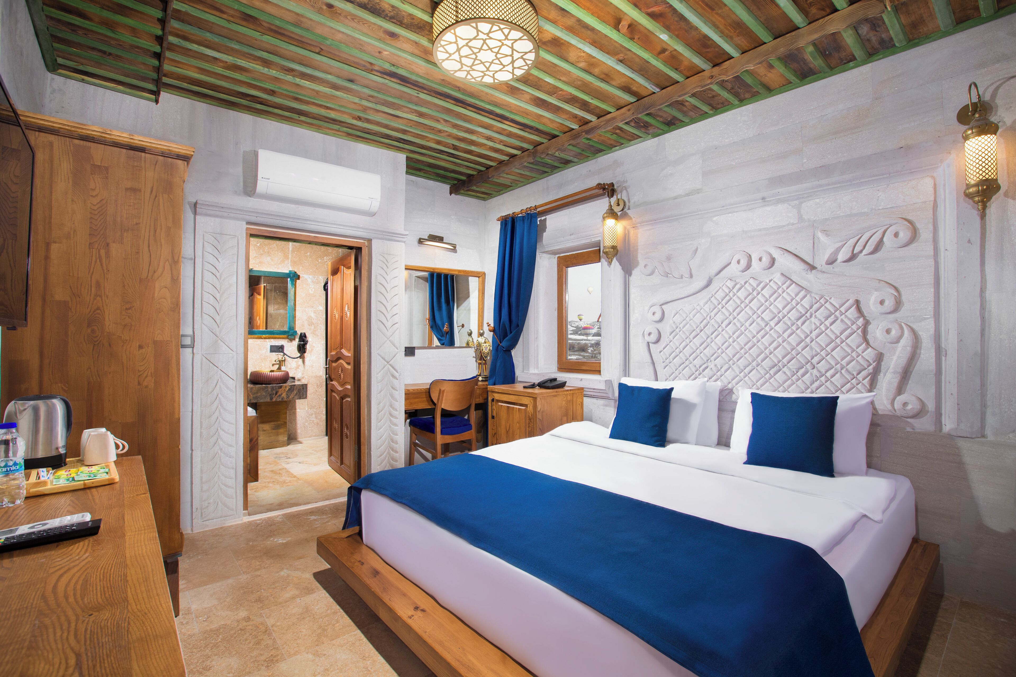 A bedroom with a large bed, wooden furniture, and a view of the bathroom.