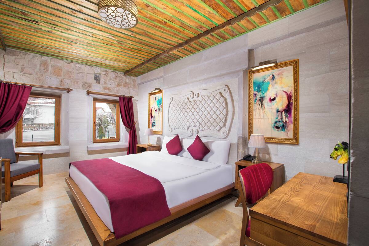 Une chambre d’hôtel avec un grand lit, un bureau en bois et un mur en pierre.