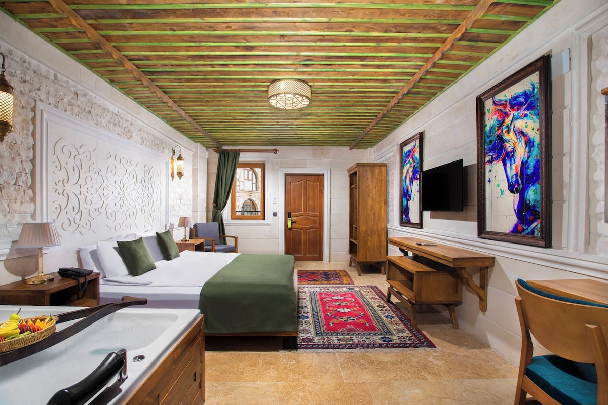 Une chambre d’hôtel équipée d’un lit, d’un bureau, d’une chaise, d’œuvres d’art et d’un téléviseur.