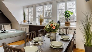 A dining area with a table set for four, surrounded by chairs, with a large window in the background. - Lumina 2-level charming apart (Warsaw)
