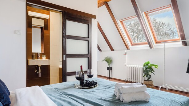 A bedroom with a bed, a nightstand, a mirror, a window, and a radiator. - Lumina 2-level charming apart (Warsaw)