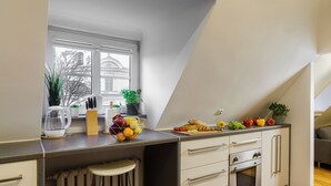 A modern kitchen with a large window, a built-in oven, and a countertop with fruits and vegetables. - Lumina 2-level charming apart (Warsaw)