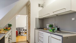 A modern kitchen with white cabinets, a stainless steel countertop, and a brick wall. - Lumina 2-level charming apart (Warsaw)