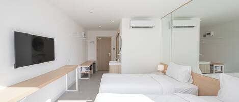 A modern hotel room with a large bed, a desk, a TV, and a bathroom visible through an open door.