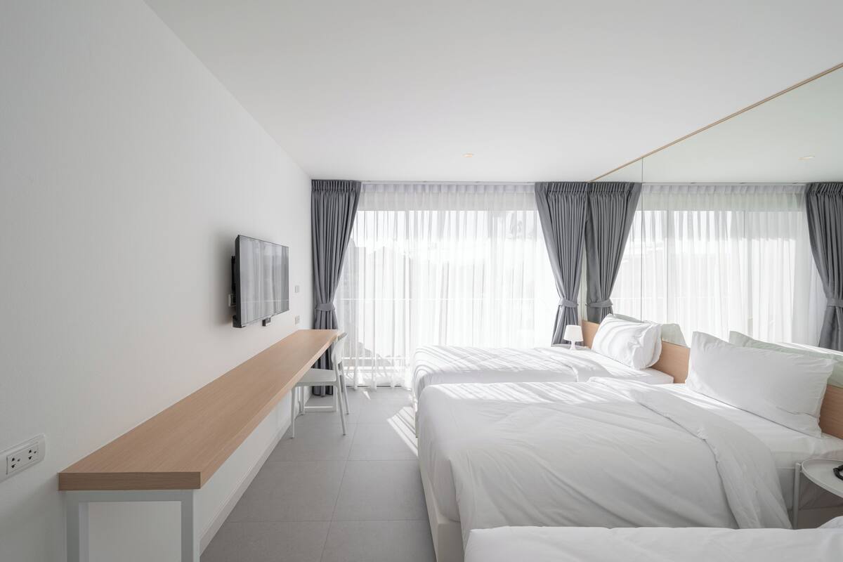 Moderni hotellihuone, jossa on suuri sänky, työpöytä ja televisio.