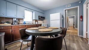 A compact kitchen with a dining area, featuring cabinets, a microwave, a refrigerator, and a table with chairs. - Affordable Cozy Retreat in Indianapolis (Indianapolis)