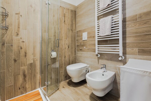 Un baño moderno con ducha, inodoro, bidé y toallero.