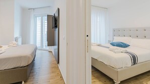 Ein Hotelzimmer mit zwei Betten, einem Flachbildfernseher und Blick ins Freie.