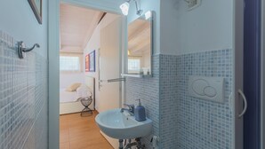 A bathroom with a white sink, a mirror, and a blue-tiled wall. - Terrazza Corallo by Wonderful Italy (Bari)