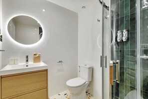 Un bagno moderno con lavandino, specchio e water bianchi.