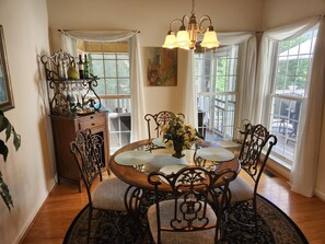 A dining area with a round table, ornate chairs, and a chandelier. There is a window with curtains and a view of the outdoors. - Spacious 5-bedroom house with kitchens and decks on both levels. (Mineral)