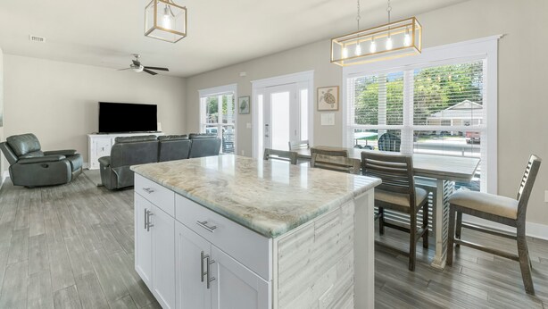 A spacious living area with a large island, a flat-screen TV, and a dining table with chairs. - 30A Beach House - Beach Bayou (Santa Rosa Beach)