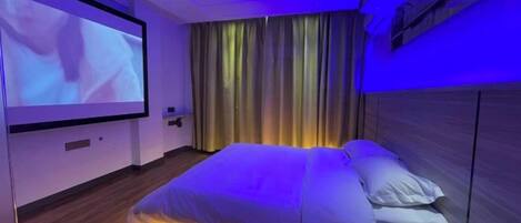 A bedroom with a bed, a television screen, and a curtain.