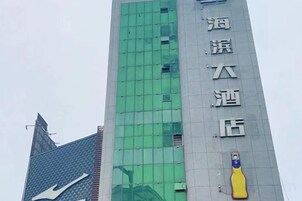 Un edificio alto con fachada verde y un gran logotipo de botella amarilla.