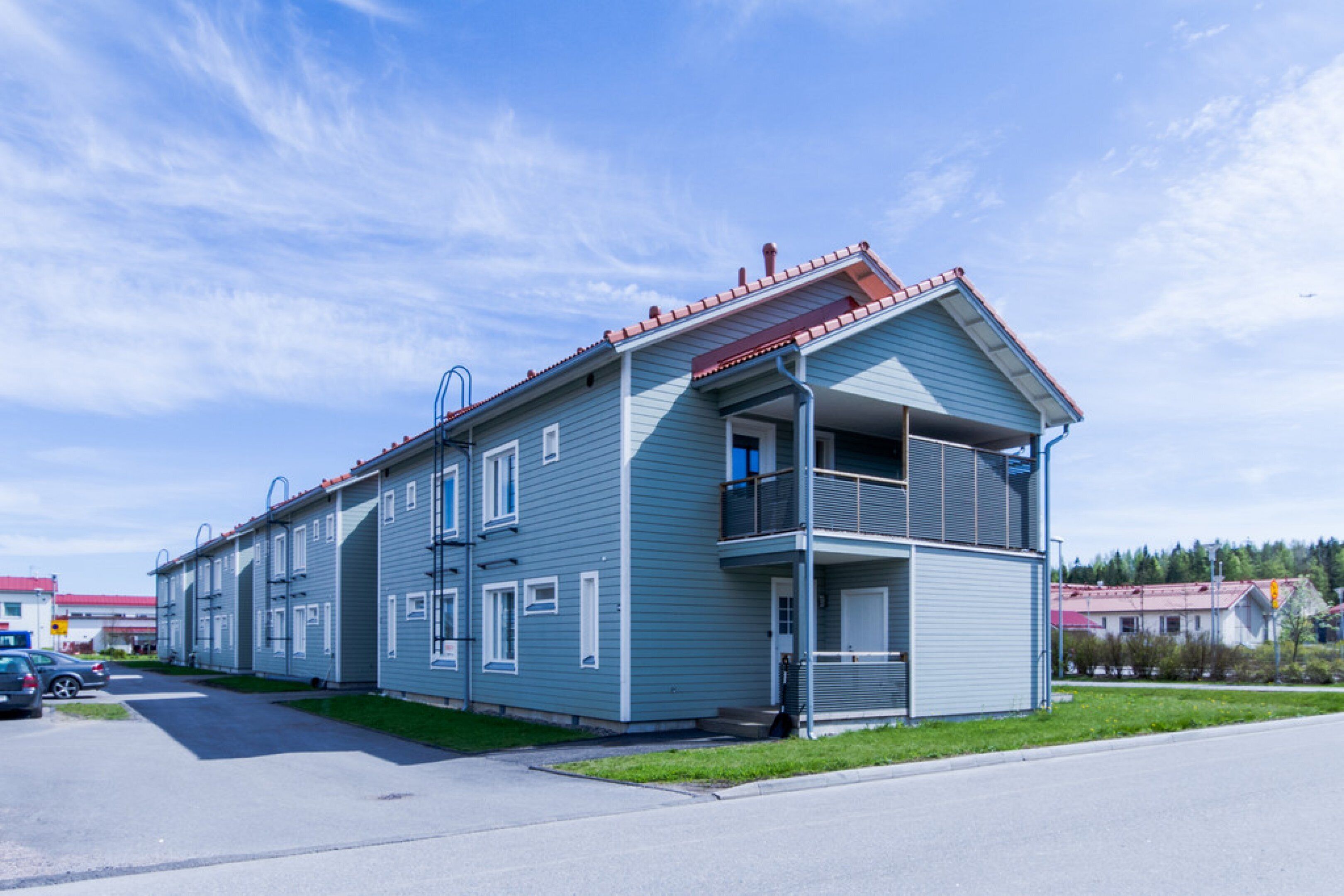 A two-story building with a balcony on the second floor, a red roof, and a clear sky.