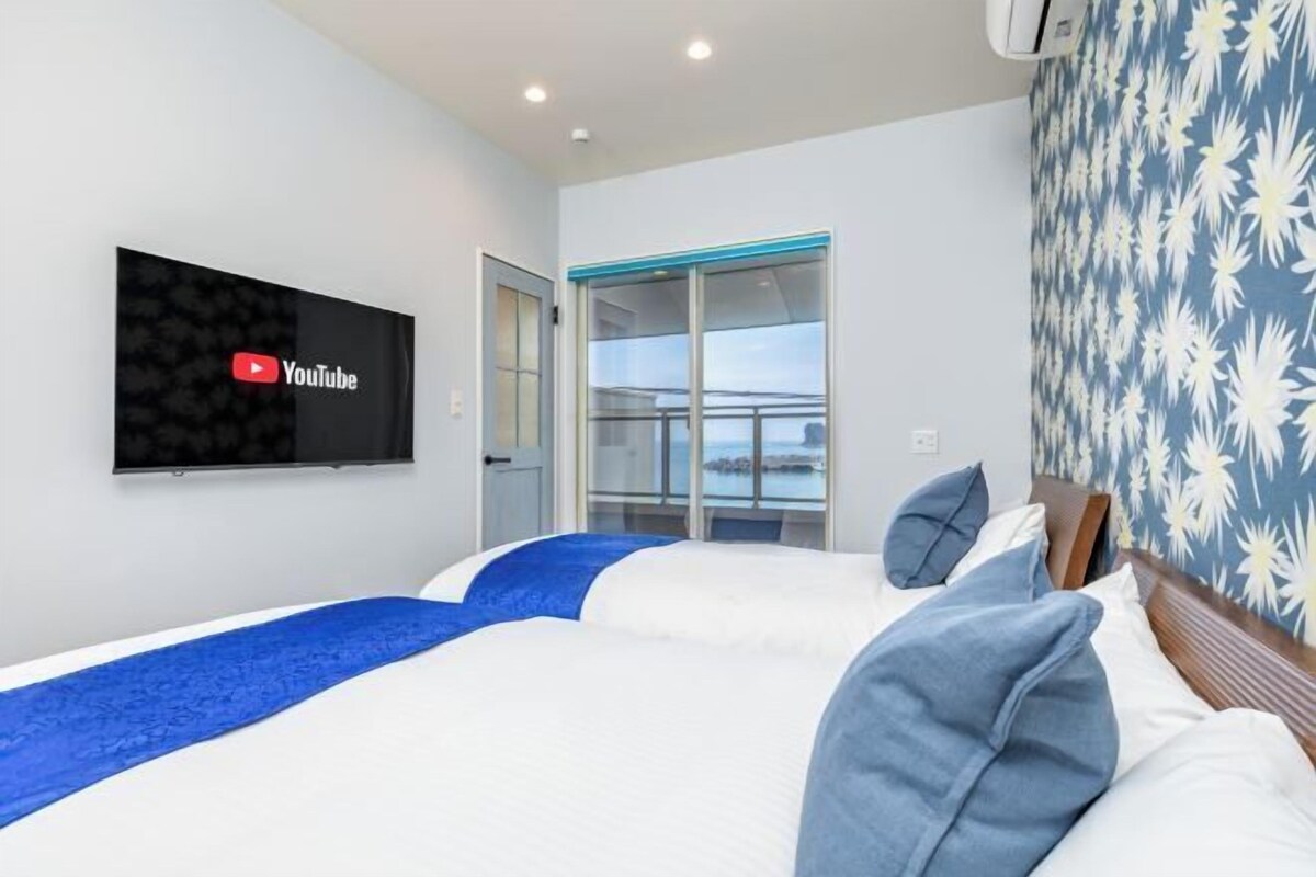 A hotel room with a bed, a TV mounted on the wall, and a window with a view.